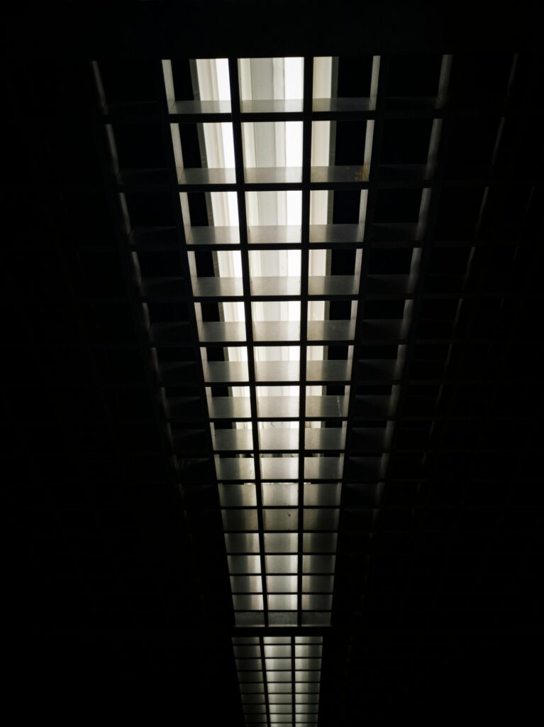 pexels-photo-2952665-2952665 Low angle view of a modern grid ceiling with bright fluorescent lights.